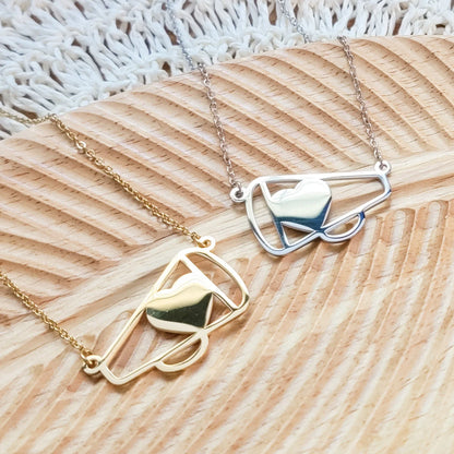 Two necklaces, one gold and one silver, on a textured wooden surface.