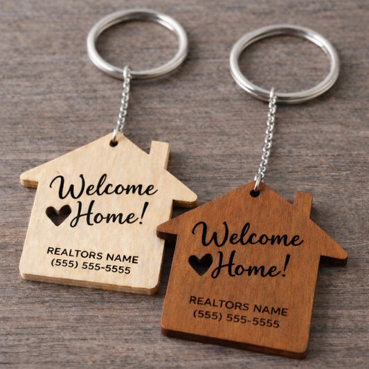 Two wooden house-shaped keychains with 'Welcome Home!' text on a wooden surface.